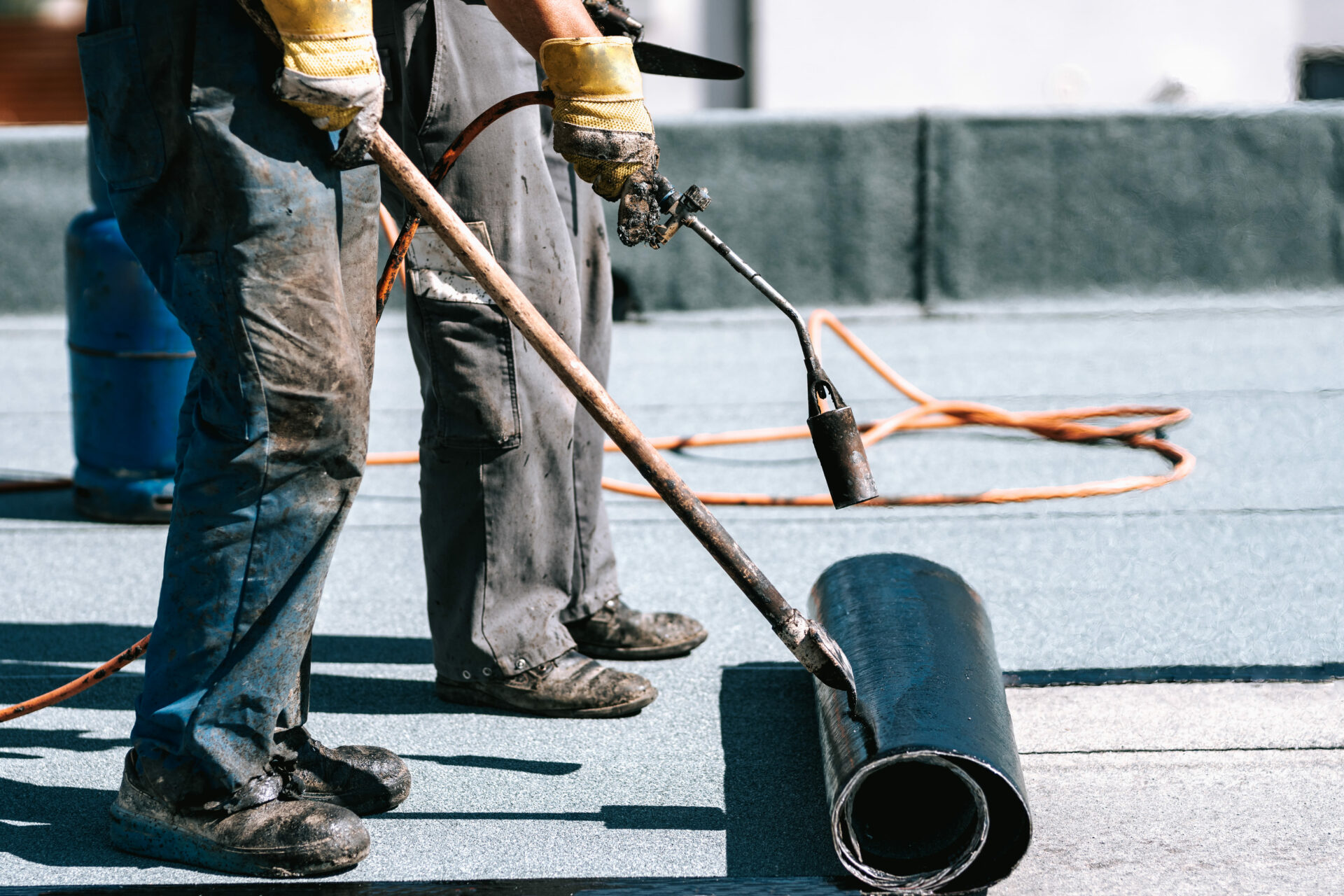 Ouvriers de construction, toitures installant des rouleaux de membrane d'étanchéité bitumineuse pour l'imperméabilisation de la nouvelle maison.